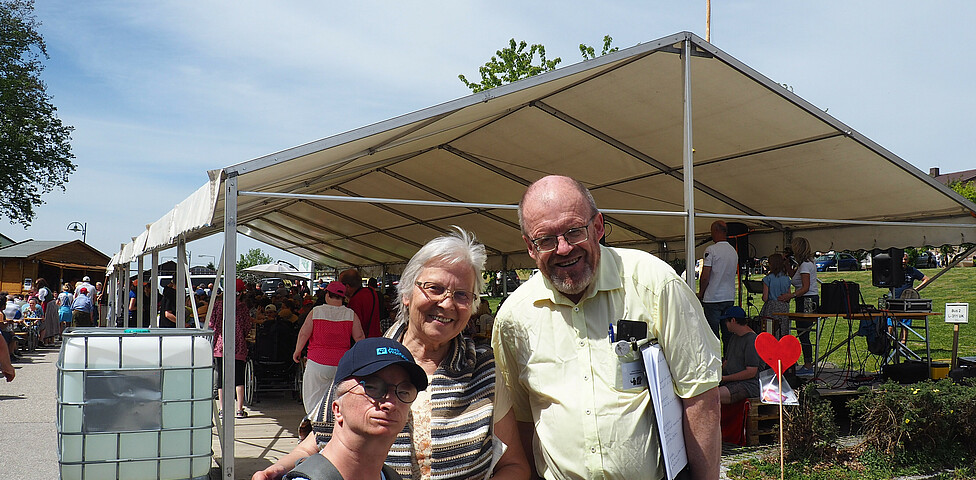 Zwei Frauen und ein Mann stehen vor einem Festzelt