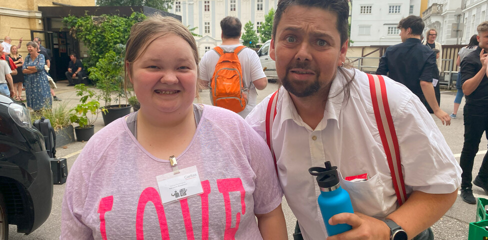 Ein Mann und eine Frau stehen nebeneinander und lachen in die Kamera. 