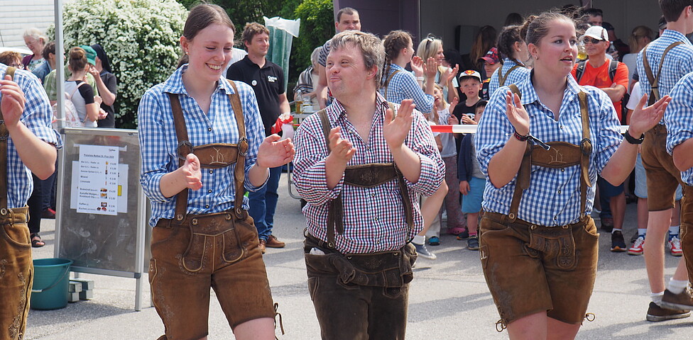 Zwei Männer und eine Frau tanzen in der Lederhosen